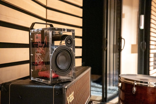 A clear Aquarius speaker sitting on top of a guitar amp.